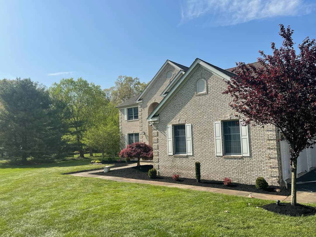 Charming brick house with landscaped yard and sunny blue sky in the background.