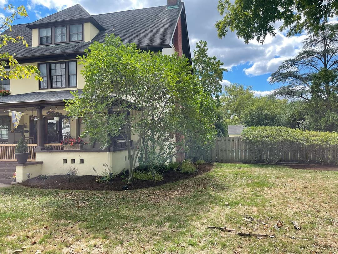 Charming house exterior with porch, landscaped yard, and blue sky, showcasing beautiful architecture.