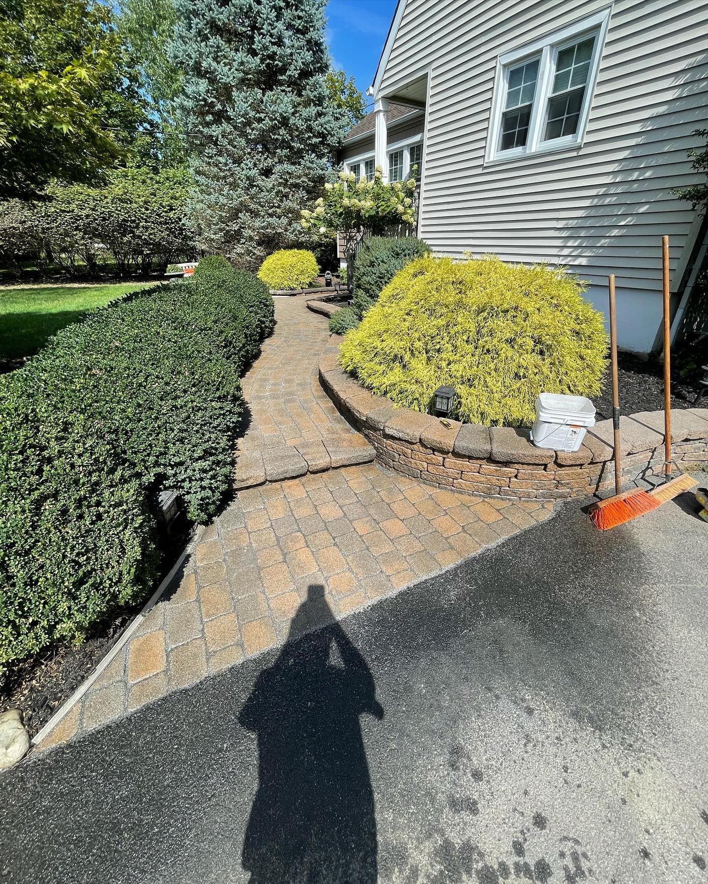 Landscape design featuring a stone walkway, lush shrubbery, and a well-maintained lawn.